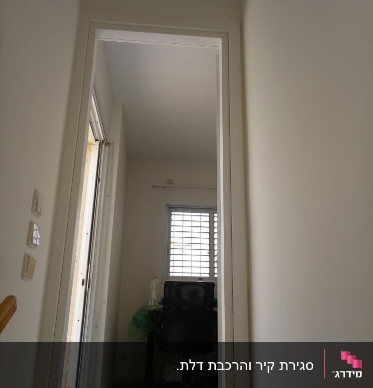 קיר גבס לבן עם דלת פתוחה וחלון סורג